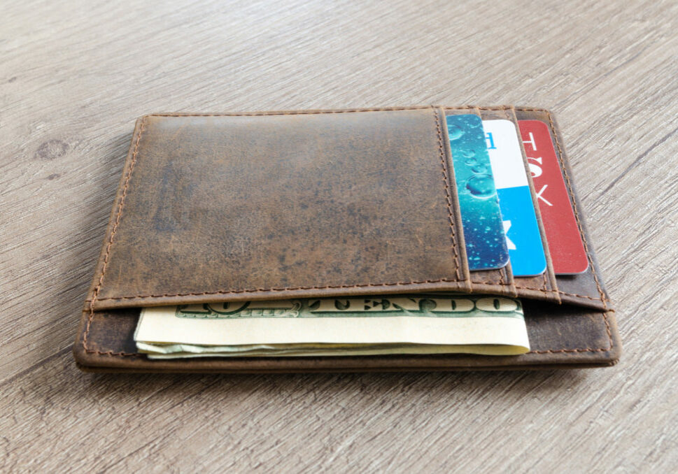 Leather wallet with cards and money inside sitting on a wooden table